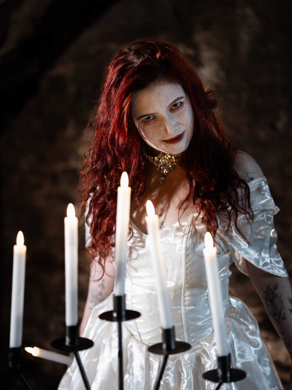 Full-length portrait under the stone archway at Portencross Castle, candelabra in frame