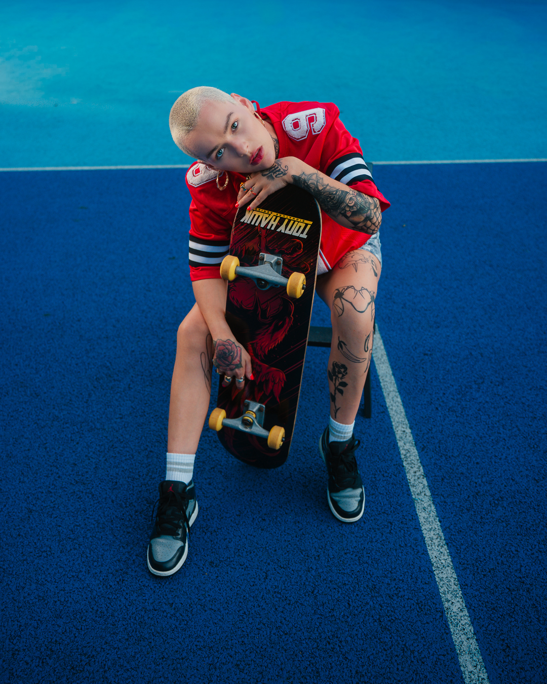 Full-length sporty editorial pose with skateboard on the blue court, Ayrshire